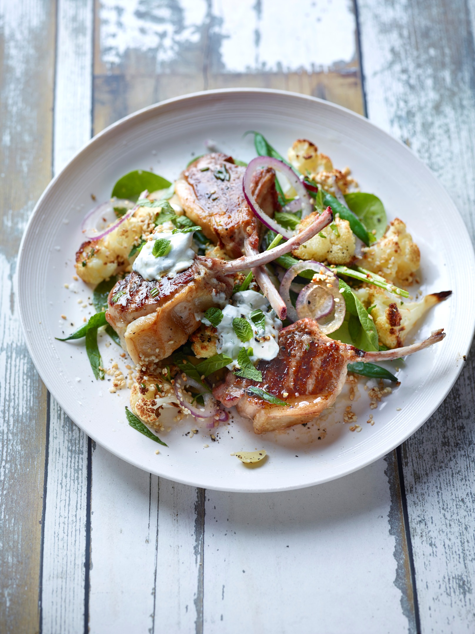 Grilled lamb chops, roast cauliflower, garlic and sesame, spinach salad and minted yoghurt by Peter Gordon